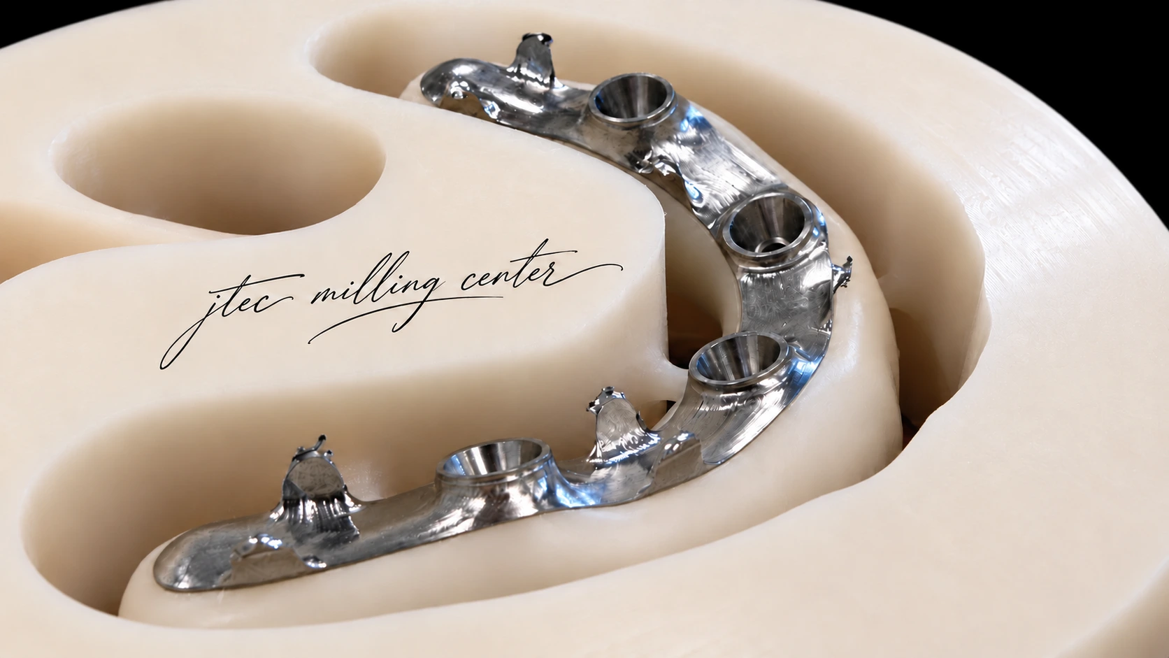Edge-to-edge close-up of a warm ivory resin milling disc and silver iBar, with a handwritten jtec milling center signature on the disc